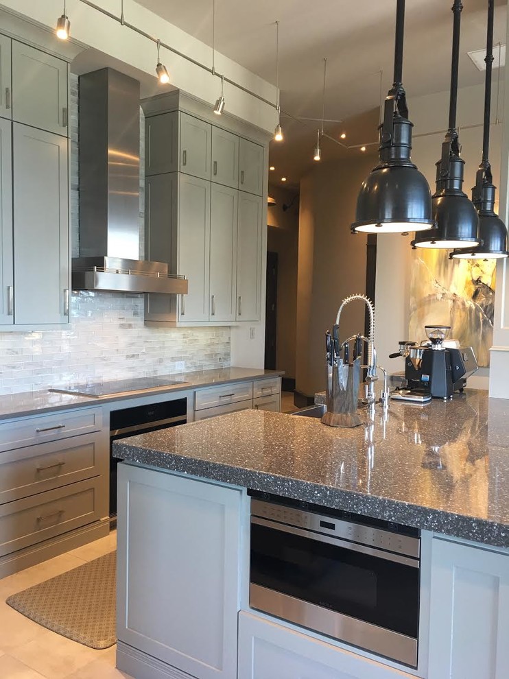 Example of a large urban l-shaped beige floor open concept kitchen design in Atlanta with a farmhouse sink, shaker cabinets, gray cabinets, recycled glass countertops, white backsplash, glass tile backsplash, stainless steel appliances and an island