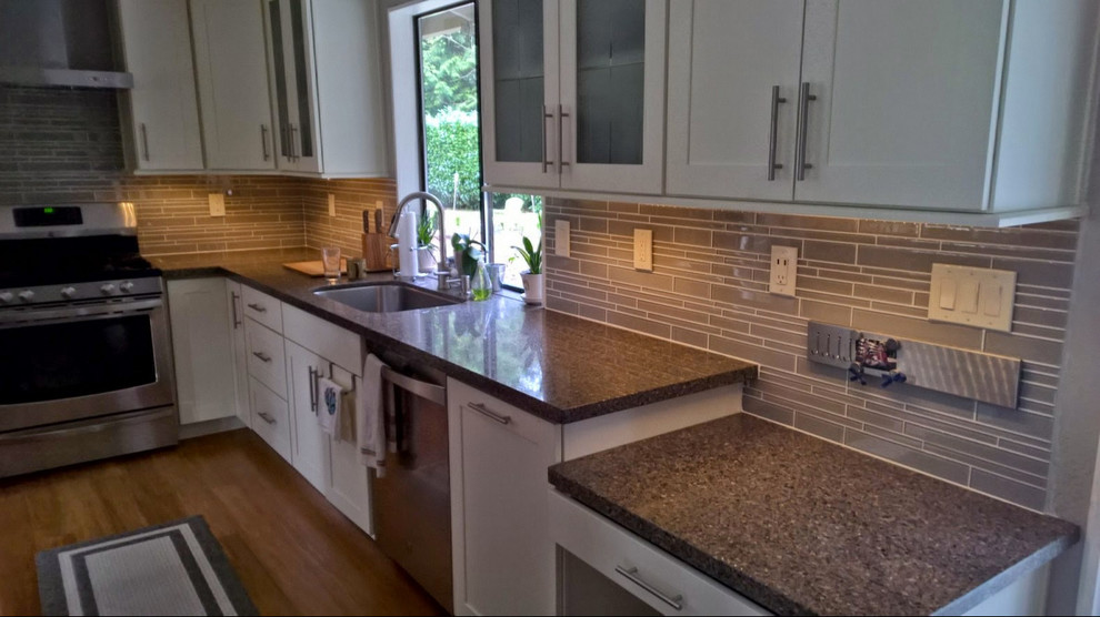 This is an example of a classic u-shaped kitchen in Seattle with a submerged sink, shaker cabinets, white cabinets, granite worktops, grey splashback, matchstick tiled splashback, stainless steel appliances and medium hardwood flooring.