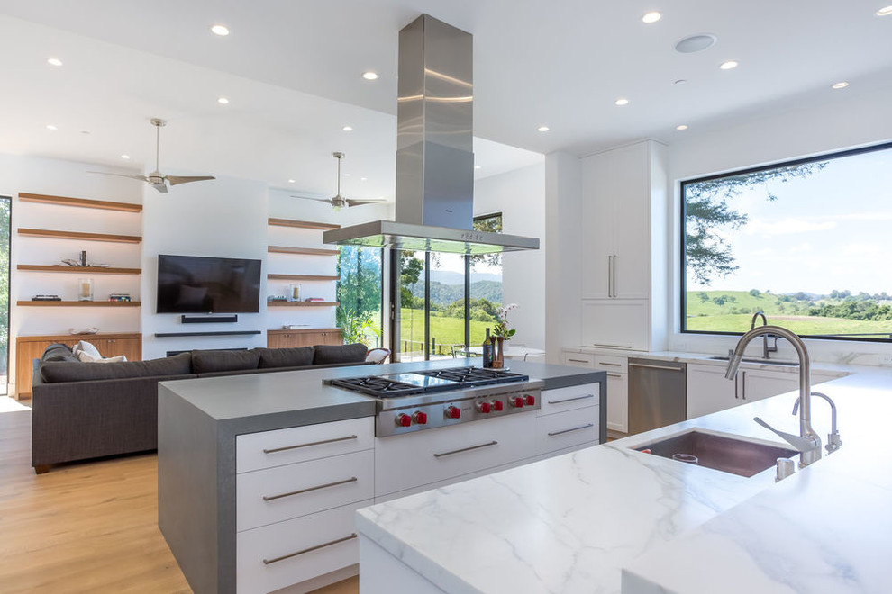 Foto på ett stort funkis kök, med en undermonterad diskho, skåp i shakerstil, vita skåp, marmorbänkskiva, grått stänkskydd, stänkskydd i marmor, rostfria vitvaror, mellanmörkt trägolv, en köksö och brunt golv