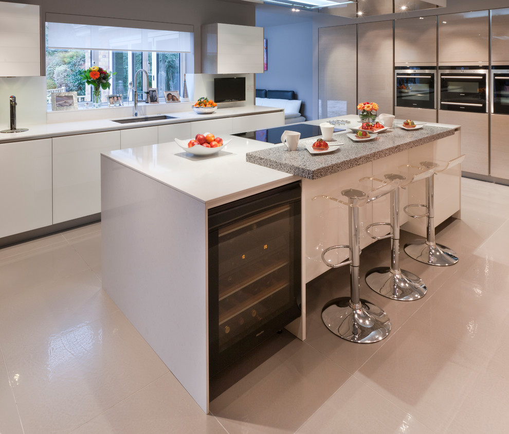 Photo of a large contemporary l-shaped open plan kitchen in London with a submerged sink, flat-panel cabinets, stainless steel appliances, ceramic flooring and an island.