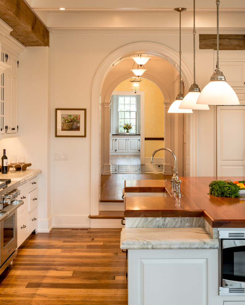 Idéer för mycket stora lantliga kök, med en rustik diskho, luckor med upphöjd panel, vita skåp, marmorbänkskiva, vitt stänkskydd, stänkskydd i stenkakel, rostfria vitvaror, mellanmörkt trägolv, en köksö och brunt golv