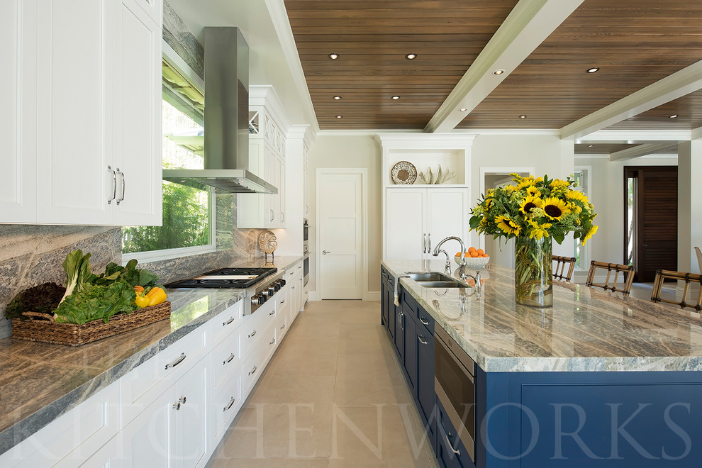 Bild på ett stort maritimt kök, med en undermonterad diskho, skåp i shakerstil, vita skåp, bänkskiva i kvartsit, blått stänkskydd, stänkskydd i sten, rostfria vitvaror, marmorgolv, en köksö och beiget golv