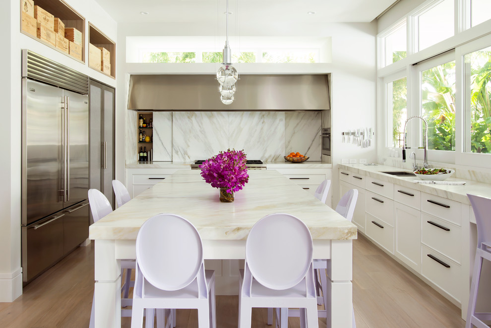 Foto på ett avskilt, stort funkis u-kök, med en undermonterad diskho, luckor med infälld panel, vita skåp, marmorbänkskiva, vitt stänkskydd, rostfria vitvaror, ljust trägolv och en köksö