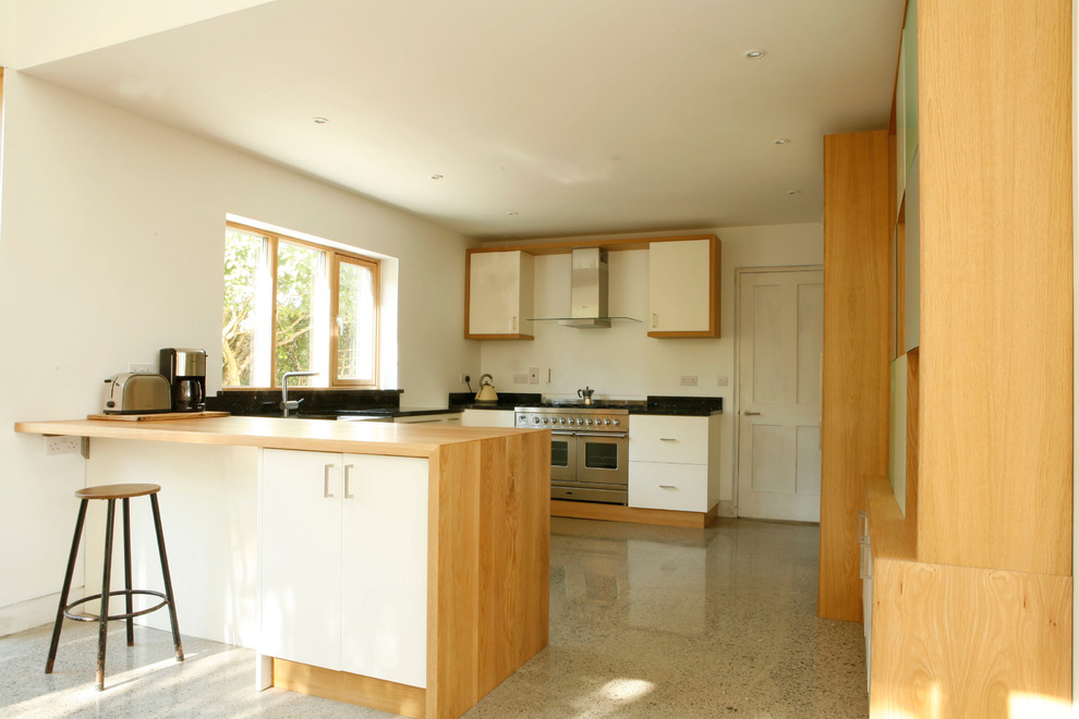 This is an example of a modern u-shaped kitchen in Dublin with a belfast sink, flat-panel cabinets and white cabinets.