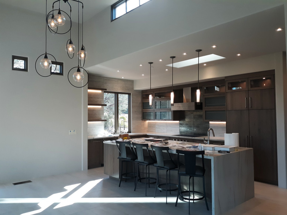 Example of a mid-sized eclectic u-shaped porcelain tile and white floor eat-in kitchen design in Phoenix with an undermount sink, flat-panel cabinets, brown cabinets, marble countertops, gray backsplash, stone tile backsplash, paneled appliances, an island and white countertops