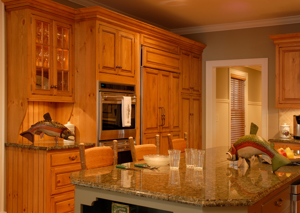 Cette image montre une grande cuisine ouverte design en L et bois clair avec un évier de ferme, un placard avec porte à panneau surélevé, une crédence beige, un électroménager en acier inoxydable, un sol en bois brun et îlot.