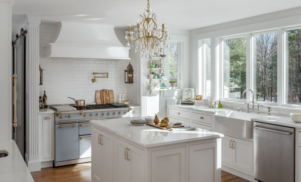 Exempel på ett mellanstort klassiskt vit vitt kök, med en rustik diskho, skåp i shakerstil, vita skåp, bänkskiva i kvarts, vitt stänkskydd, stänkskydd i tunnelbanekakel, mellanmörkt trägolv, en köksö, rostfria vitvaror och brunt golv