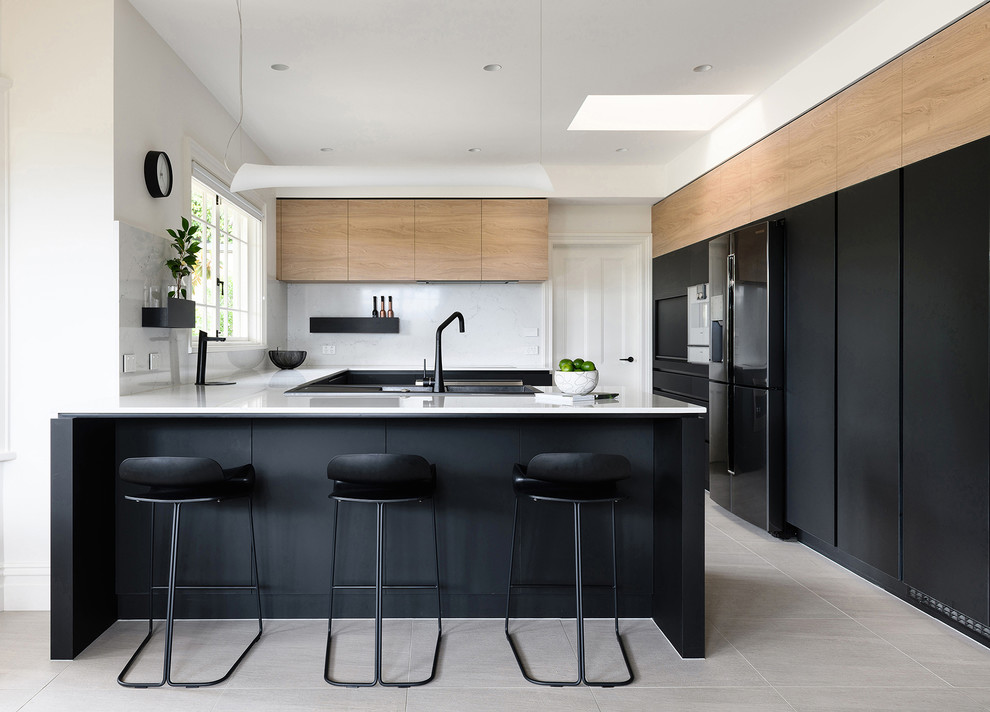 Moderne Küche in U-Form mit flächenbündigen Schrankfronten, schwarzen Schränken, Küchenrückwand in Weiß, schwarzen Elektrogeräten, Halbinsel, beigem Boden und weißer Arbeitsplatte in Hobart