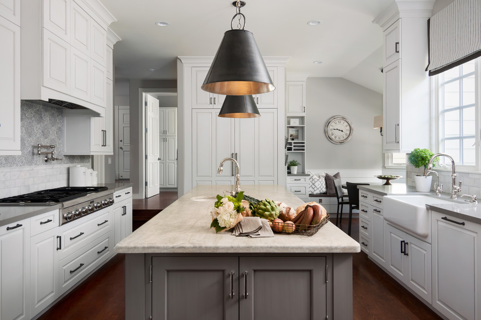 Photo of a traditional grey and white kitchen in Orange County with a belfast sink, raised-panel cabinets, white cabinets, multi-coloured splashback, stainless steel appliances, medium hardwood flooring and an island.