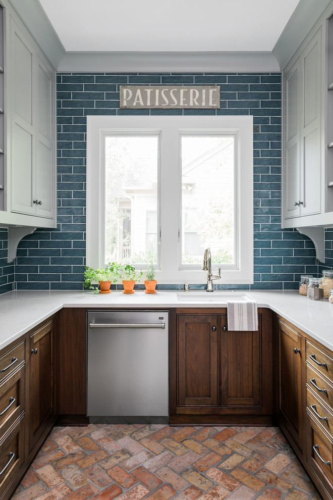 Klassisk inredning av ett mellanstort vit vitt kök, med en undermonterad diskho, släta luckor, grå skåp, bänkskiva i kvarts, blått stänkskydd, stänkskydd i keramik, rostfria vitvaror, tegelgolv och rött golv