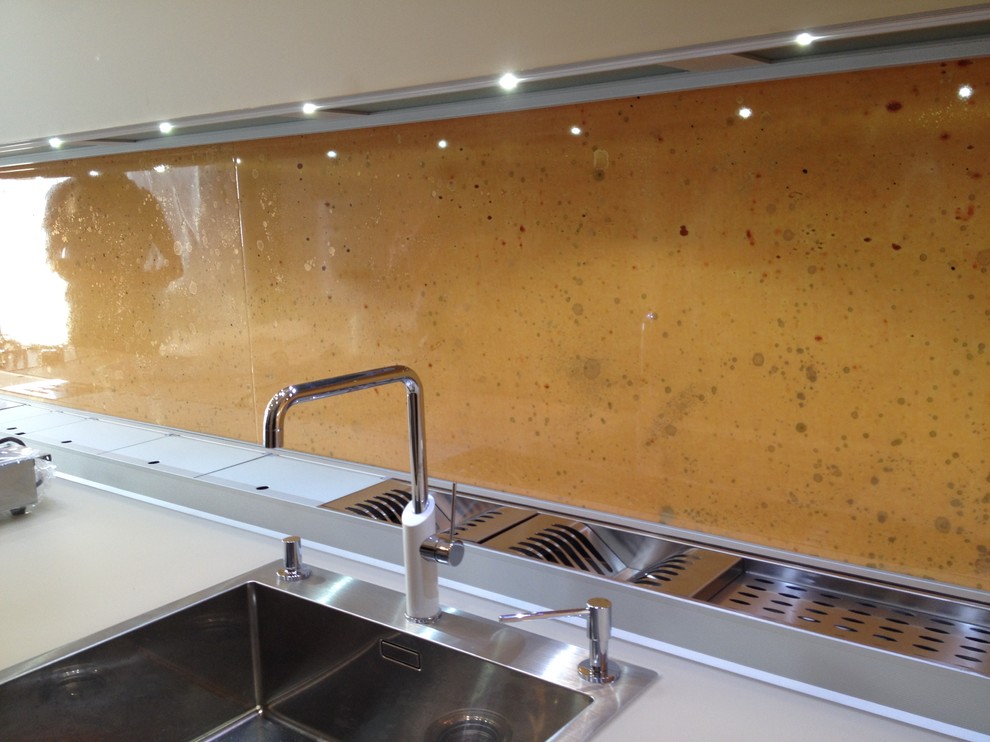 Immagine di una cucina minimalista con lavello integrato, ante di vetro, ante beige, top in vetro e paraspruzzi multicolore