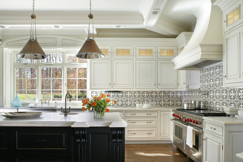 Inspiration för klassiska vitt l-kök, med luckor med profilerade fronter, vita skåp, flerfärgad stänkskydd, stänkskydd i cementkakel, rostfria vitvaror, mörkt trägolv, en köksö och brunt golv