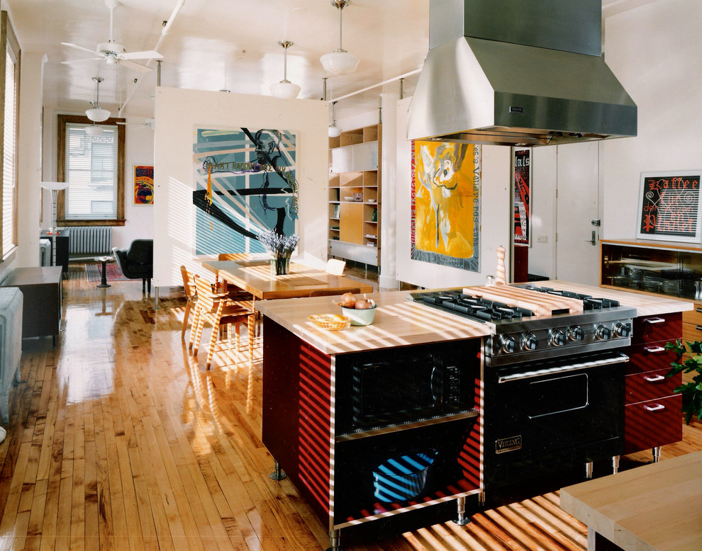 ニューヨークにあるラグジュアリーな小さなミッドセンチュリースタイルのおしゃれなキッチン (シングルシンク、フラットパネル扉のキャビネット、赤いキャビネット、木材カウンター、黒い調理設備、淡色無垢フローリング) の写真