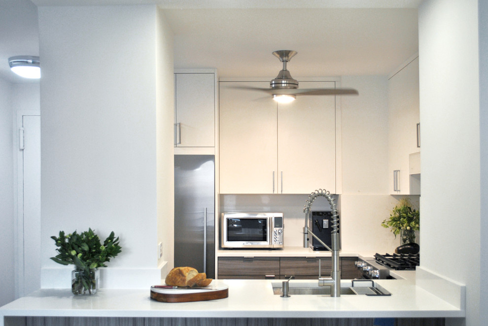 Example of a small minimalist u-shaped light wood floor eat-in kitchen design in New York with an undermount sink, flat-panel cabinets, gray cabinets, quartz countertops, white backsplash, stone slab backsplash, stainless steel appliances, a peninsula and white countertops