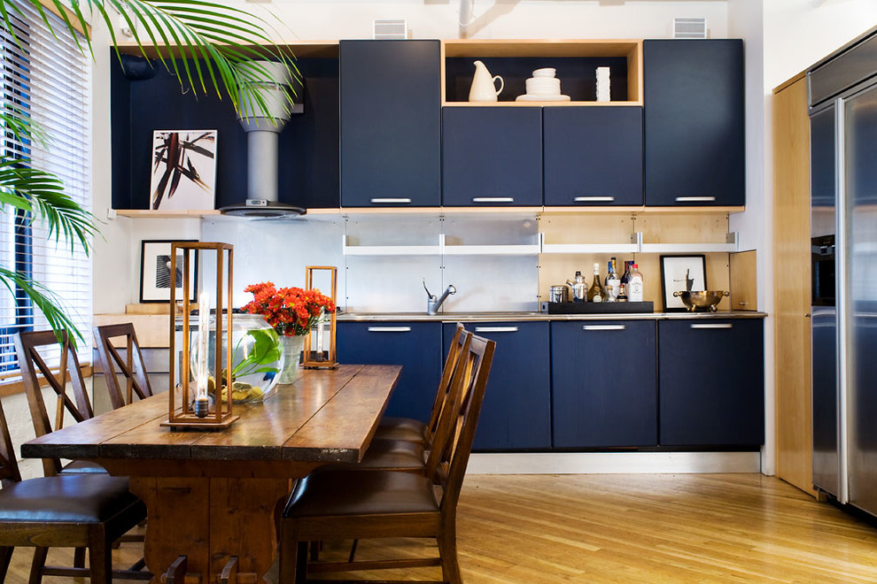 Moderne Wohnküche ohne Insel mit flächenbündigen Schrankfronten, blauen Schränken, Küchenrückwand in Metallic, Küchengeräten aus Edelstahl und braunem Holzboden in New York