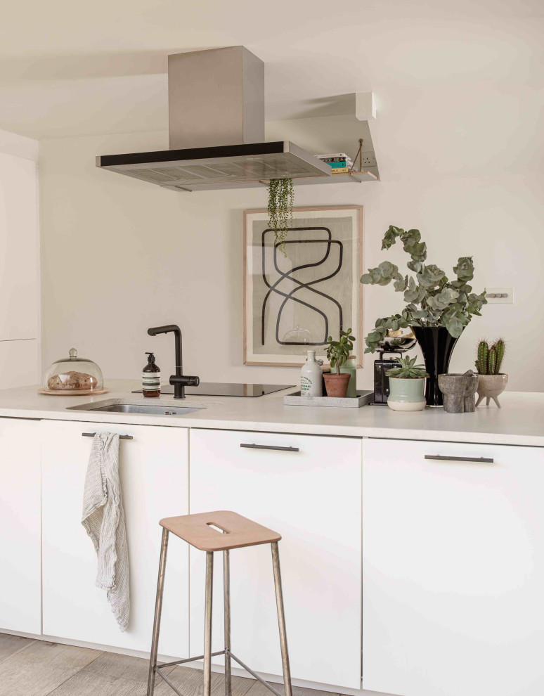 Photo of a medium sized scandinavian u-shaped open plan kitchen in Essex with flat-panel cabinets, white cabinets, concrete worktops, black appliances, an island and grey worktops.