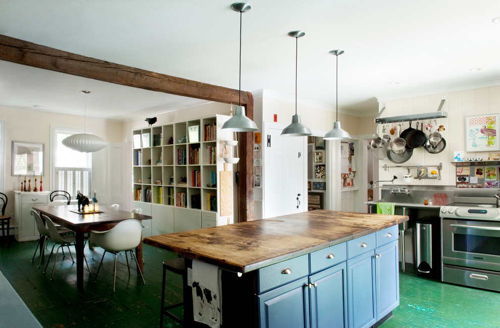 Cette image montre une cuisine américaine chalet avec un électroménager en acier inoxydable, un plan de travail en bois, un placard avec porte à panneau surélevé, des portes de placard bleues, parquet peint et un sol vert.