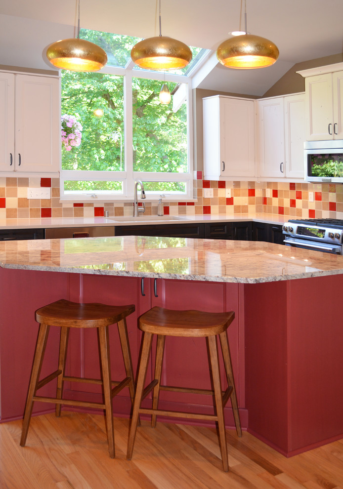 Example of a mid-sized eclectic l-shaped light wood floor eat-in kitchen design in Seattle with an undermount sink, recessed-panel cabinets, white cabinets, granite countertops, multicolored backsplash, ceramic backsplash, stainless steel appliances and an island