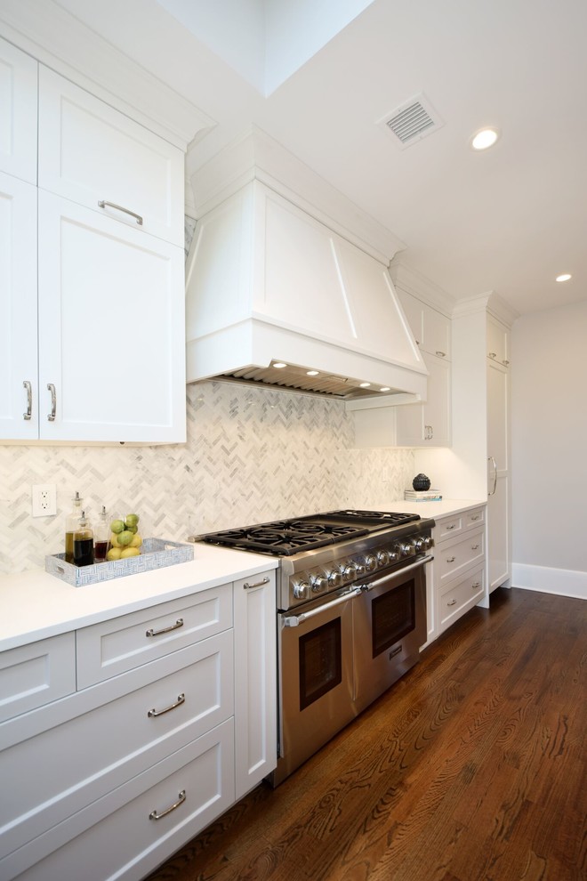 Bild på ett mellanstort vintage vit vitt kök, med en rustik diskho, skåp i shakerstil, vita skåp, marmorbänkskiva, vitt stänkskydd, stänkskydd i porslinskakel, rostfria vitvaror, mellanmörkt trägolv, en köksö och brunt golv