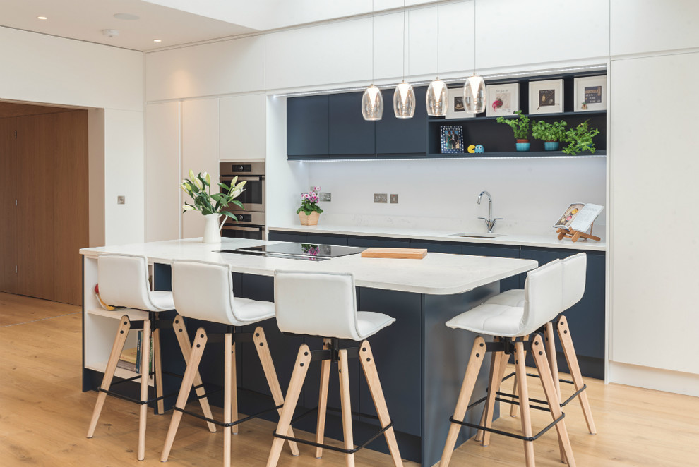 Idée de décoration pour une cuisine américaine parallèle minimaliste de taille moyenne avec un plan de travail en quartz, îlot et un plan de travail blanc.