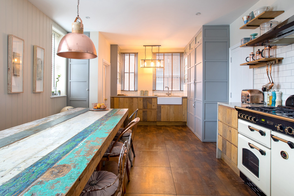 Inspiration for a country l-shaped kitchen/diner in London with a belfast sink, medium wood cabinets, white splashback, metro tiled splashback, no island, brown floors and flat-panel cabinets.
