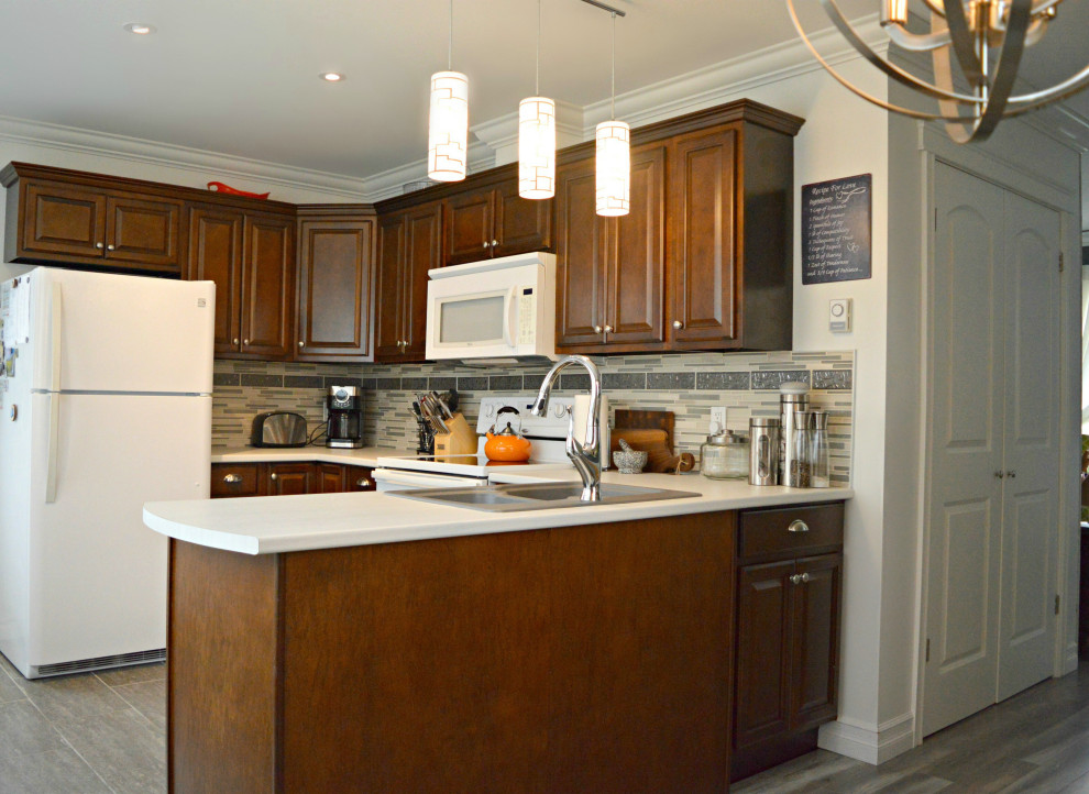 Foto på ett litet maritimt vit kök, med en dubbel diskho, luckor med upphöjd panel, skåp i mörkt trä, laminatbänkskiva, grått stänkskydd, stänkskydd i porslinskakel, vita vitvaror, klinkergolv i keramik, en köksö och grått golv