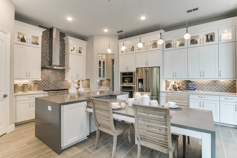 Klassische Wohnküche mit Keramikboden, grauem Boden, Schrankfronten im Shaker-Stil, weißen Schränken, Küchenrückwand in Grau, Küchengeräten aus Edelstahl, Kücheninsel und grauer Arbeitsplatte in Houston