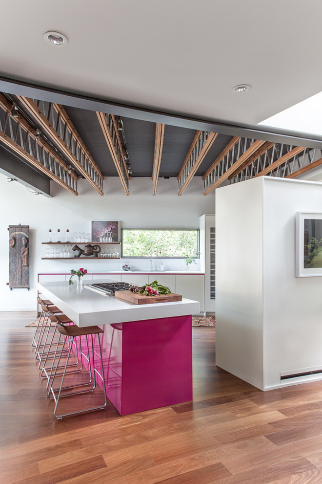 Moderne Küche mit flächenbündigen Schrankfronten, weißen Schränken, braunem Holzboden und Kücheninsel in Austin