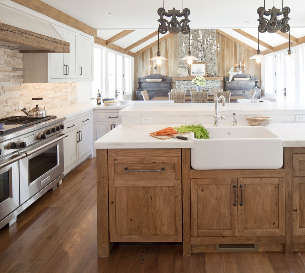 Mid-sized beach style l-shaped medium tone wood floor eat-in kitchen photo in Providence with a farmhouse sink, recessed-panel cabinets, light wood cabinets, beige backsplash, stone tile backsplash, stainless steel appliances and an island