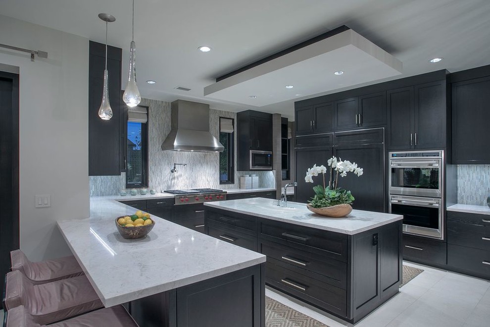 Example of a mid-sized eclectic u-shaped porcelain tile and white floor open concept kitchen design in Los Angeles with an undermount sink, recessed-panel cabinets, dark wood cabinets, marble countertops, stainless steel appliances, two islands and white countertops