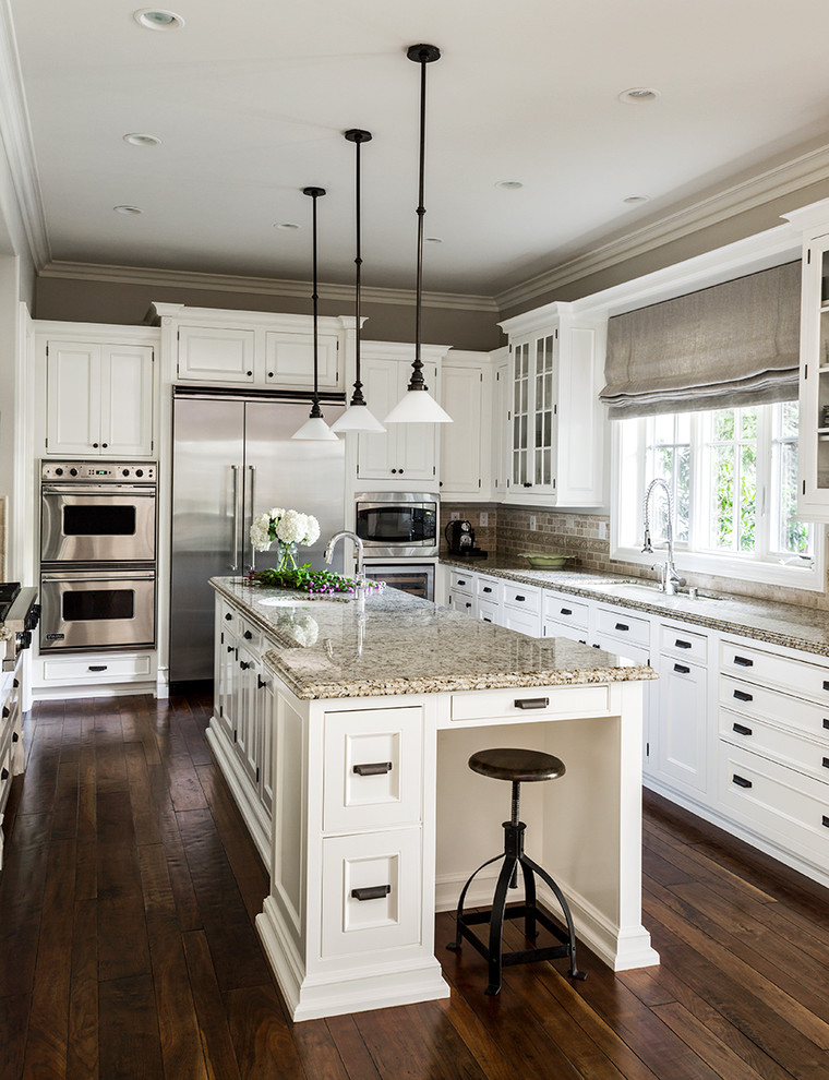 Example of a classic u-shaped dark wood floor kitchen design in Los Angeles with recessed-panel cabinets, white cabinets, beige backsplash, stainless steel appliances and an island