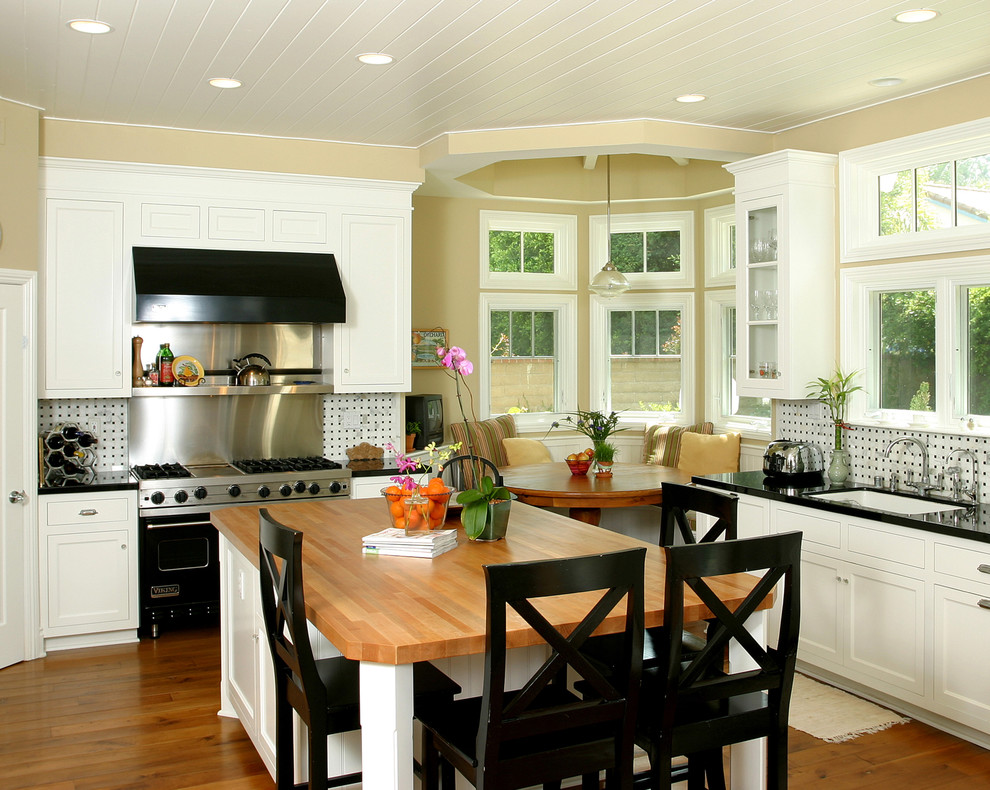 Klassische Küche mit Arbeitsplatte aus Holz, Schrankfronten im Shaker-Stil, weißen Schränken und schwarzen Elektrogeräten in Orange County