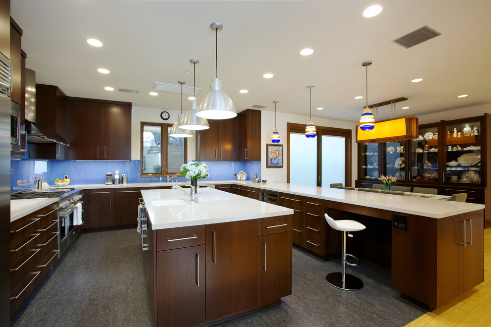 Example of a trendy u-shaped eat-in kitchen design in Orange County with an undermount sink, flat-panel cabinets, dark wood cabinets, blue backsplash, glass sheet backsplash and stainless steel appliances