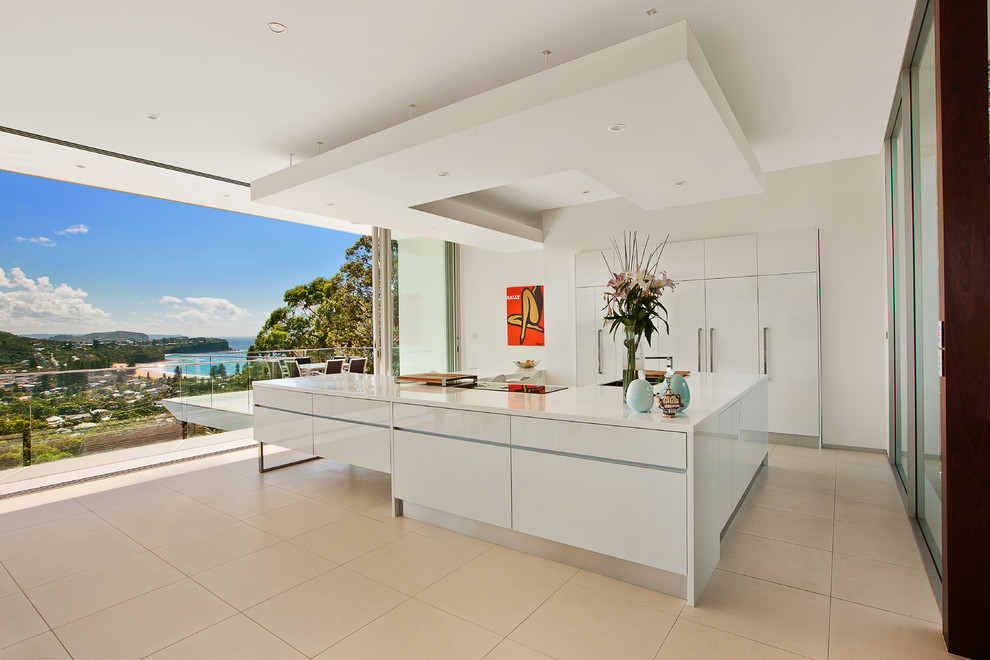 Photo of a large contemporary open plan kitchen in Sydney with flat-panel cabinets, white cabinets, integrated appliances, an island and beige floors.