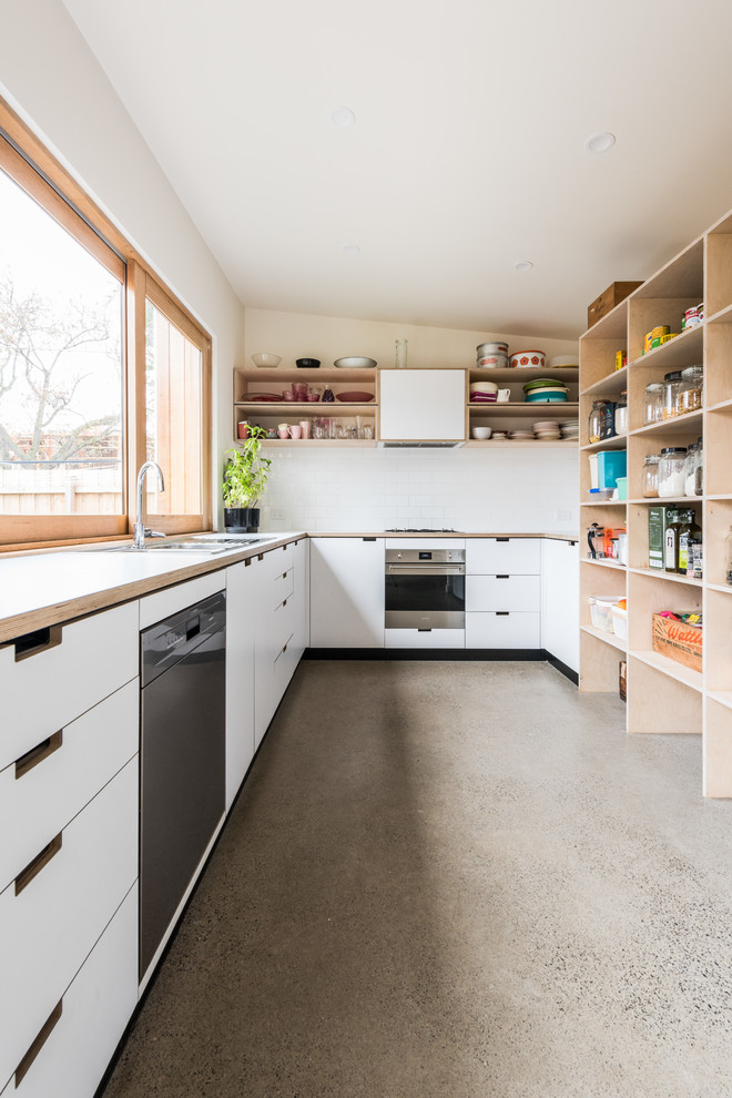 Contemporary galley kitchen/diner in Melbourne with a double-bowl sink, flat-panel cabinets, white cabinets, wood worktops, stainless steel appliances, concrete flooring, no island and white worktops.