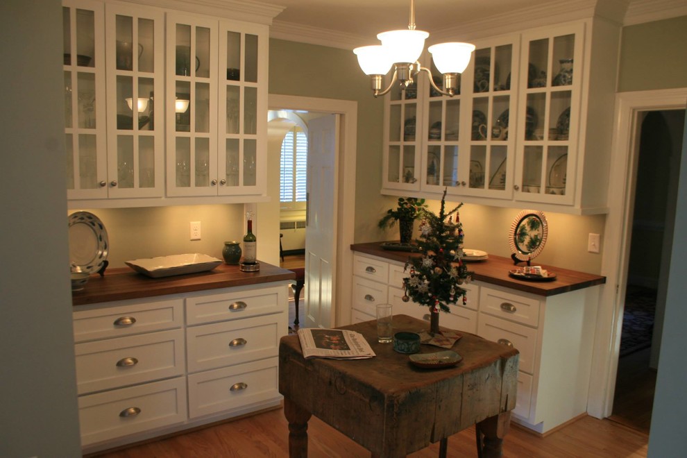 Modelo de cocina clásica con armarios estilo shaker, puertas de armario blancas y encimera de madera