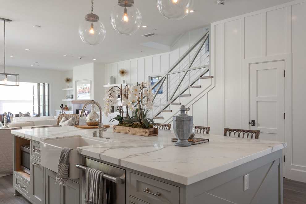 Immagine di una grande cucina costiera con ante bianche, top in marmo, paraspruzzi con piastrelle di vetro, elettrodomestici in acciaio inossidabile e parquet chiaro