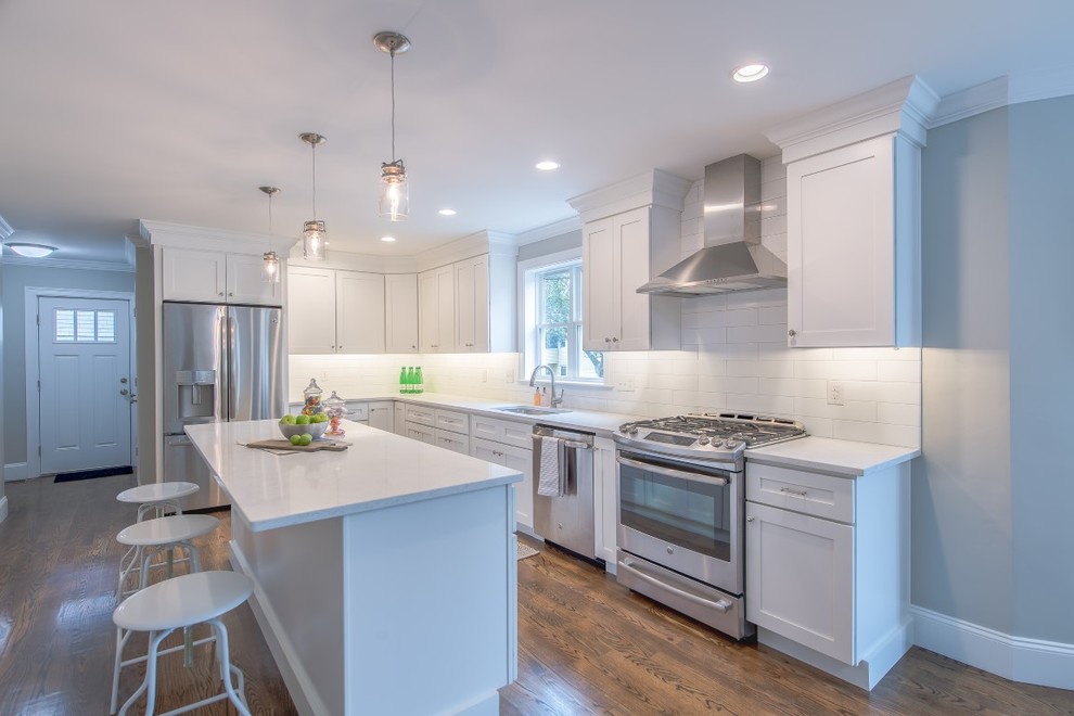 Large transitional l-shaped medium tone wood floor open concept kitchen photo in Boston with an undermount sink, shaker cabinets, white cabinets, quartzite countertops, white backsplash, subway tile backsplash, stainless steel appliances and an island
