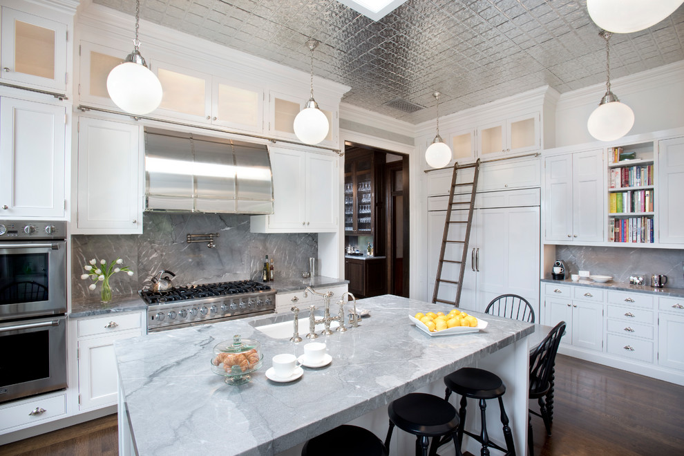 Bild på ett avskilt, mellanstort vintage u-kök, med en undermonterad diskho, luckor med infälld panel, vita skåp, marmorbänkskiva, blått stänkskydd, stänkskydd i marmor, rostfria vitvaror, mörkt trägolv, en köksö och brunt golv