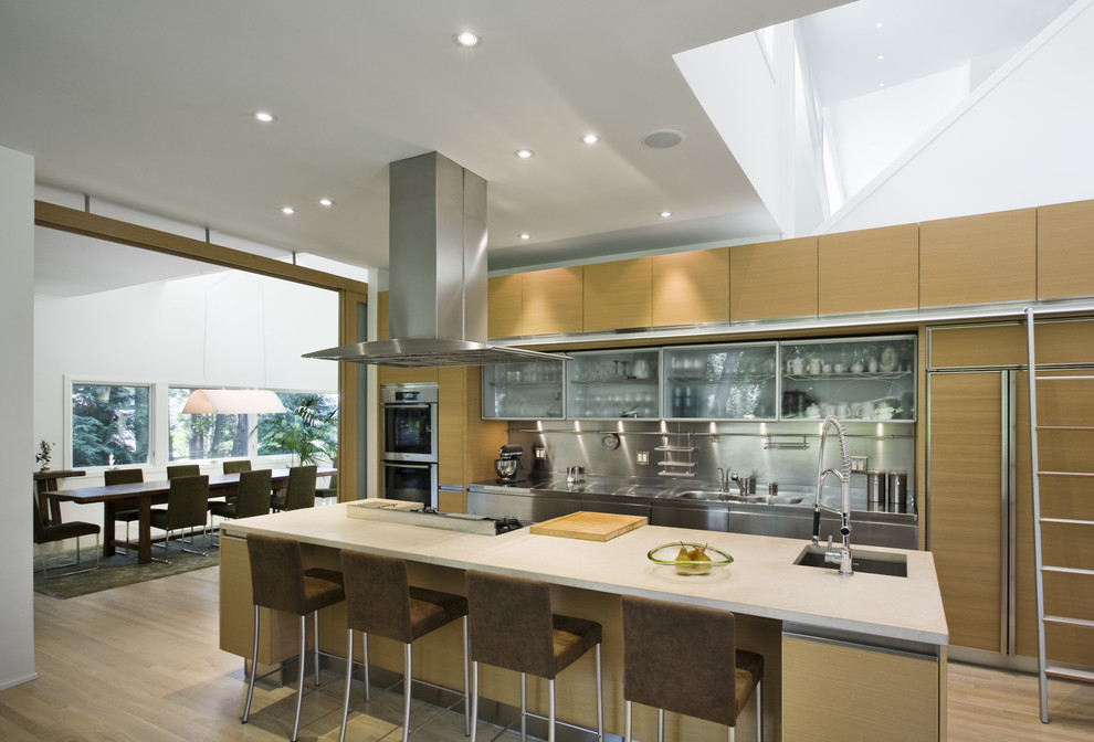 Esempio di una cucina parallela design con lavello integrato, ante lisce, ante in legno chiaro, top in acciaio inossidabile, paraspruzzi a effetto metallico e elettrodomestici in acciaio inossidabile