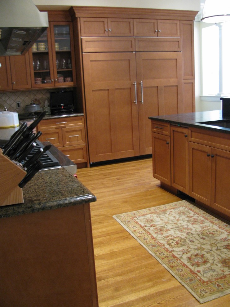 Exempel på ett mellanstort klassiskt kök, med luckor med infälld panel, skåp i mörkt trä, bänkskiva i täljsten, beige stänkskydd, stänkskydd i keramik, integrerade vitvaror, ljust trägolv, en köksö och brunt golv