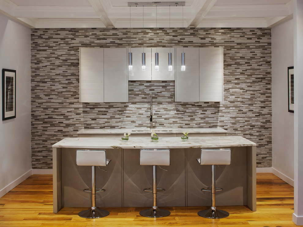Cette image montre une cuisine linéaire design en inox fermée et de taille moyenne avec un placard à porte plane, plan de travail en marbre, une crédence métallisée, une crédence en dalle métallique, un sol en bois brun et îlot.