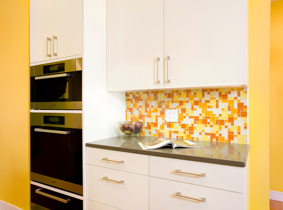 Zweizeilige Moderne Küche mit Unterbauwaschbecken, flächenbündigen Schrankfronten, weißen Schränken, Quarzwerkstein-Arbeitsplatte, Glasrückwand und Küchengeräten aus Edelstahl in Boston