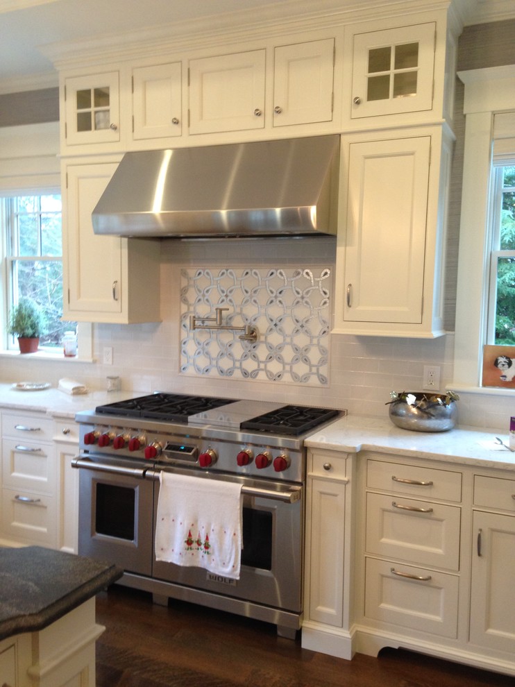 Photo of a large traditional u-shaped kitchen/diner in Boston with a submerged sink, beaded cabinets, white cabinets, engineered stone countertops, white splashback, metro tiled splashback, white appliances, medium hardwood flooring and an island.