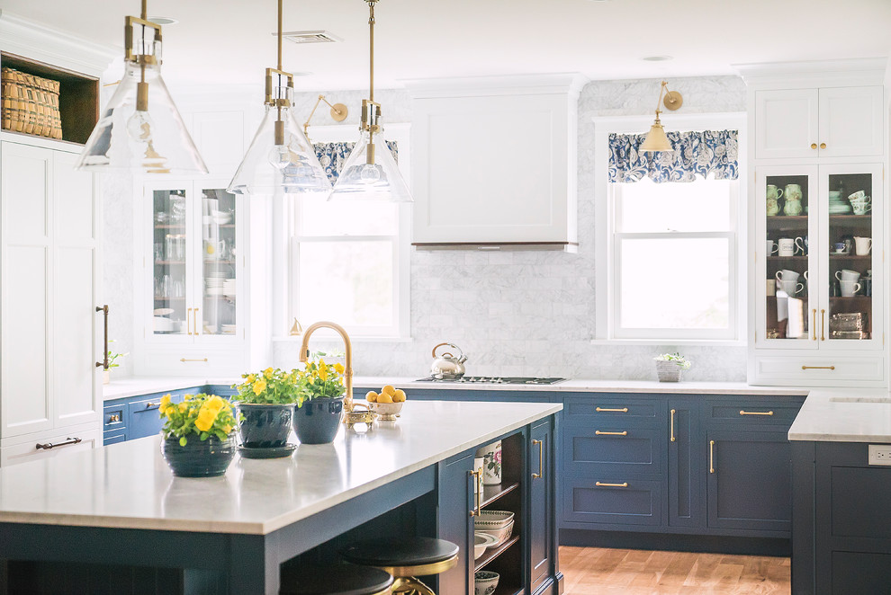 Klassisk inredning av ett stort vit vitt u-kök, med en rustik diskho, skåp i shakerstil, blå skåp, vitt stänkskydd, stänkskydd i marmor, rostfria vitvaror, mellanmörkt trägolv, en köksö och brunt golv