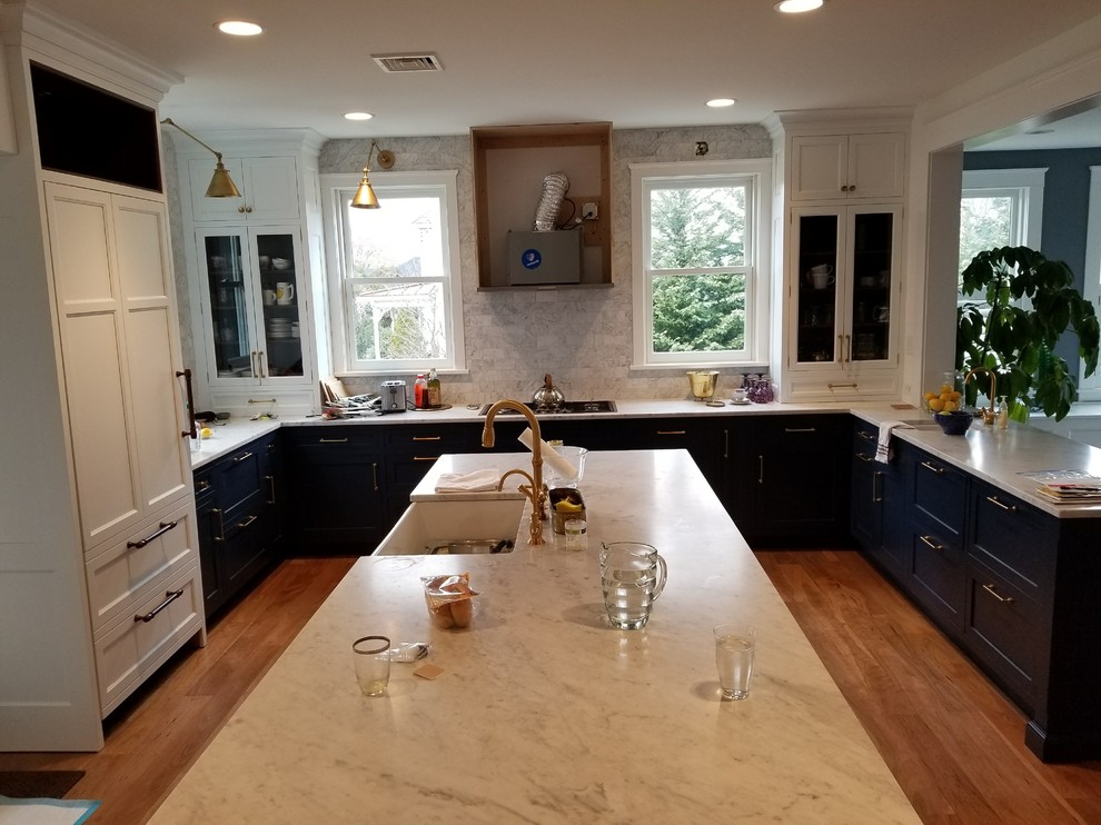Mid-sized trendy u-shaped light wood floor and brown floor eat-in kitchen photo in Philadelphia with a farmhouse sink, shaker cabinets, gray cabinets, quartz countertops, gray backsplash, ceramic backsplash, an island and white countertops