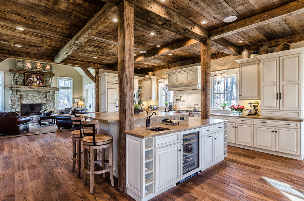 This is an example of a rustic l-shaped open plan kitchen in New York with a submerged sink, raised-panel cabinets, beige cabinets, white splashback and integrated appliances.