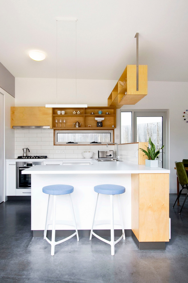 Bild på ett mellanstort funkis kök, med en dubbel diskho, öppna hyllor, skåp i ljust trä, bänkskiva i koppar, vitt stänkskydd, stänkskydd i keramik, rostfria vitvaror, en halv köksö och betonggolv