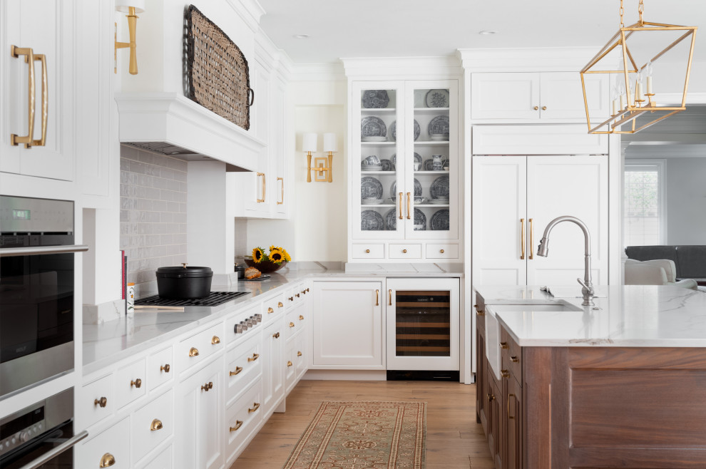 Large transitional l-shaped light wood floor and gray floor kitchen photo in Philadelphia with a farmhouse sink, shaker cabinets, white cabinets, quartz countertops, gray backsplash, ceramic backsplash, stainless steel appliances, an island and white countertops