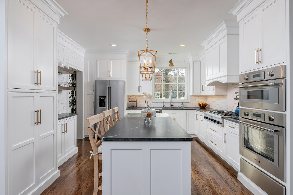 Inspiration for a large transitional u-shaped medium tone wood floor and brown floor eat-in kitchen remodel in Philadelphia with an undermount sink, beaded inset cabinets, white cabinets, quartzite countertops, white backsplash, subway tile backsplash, stainless steel appliances, an island and black countertops